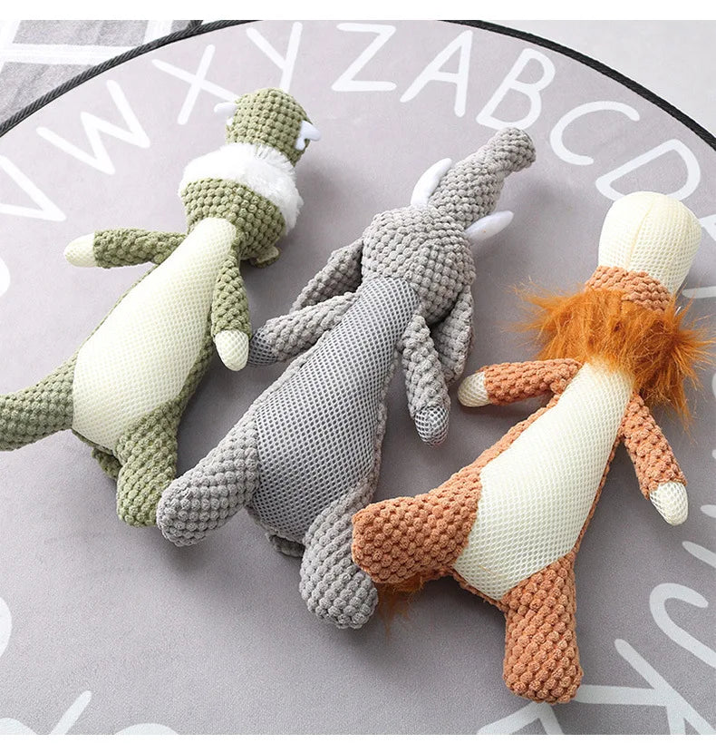 Three knitted animal dog chew toys underbellies (a green wolf, an gray elephant, and a orange lion) on a surface with a lettered background