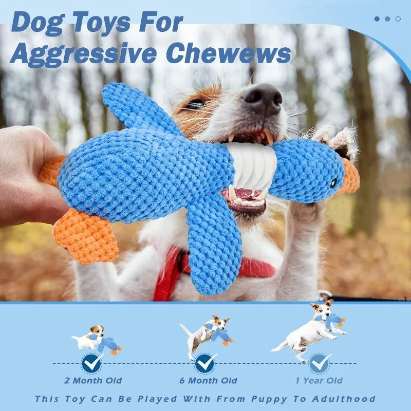 Dog playing with a blue knitted goose chew toy outdoors.